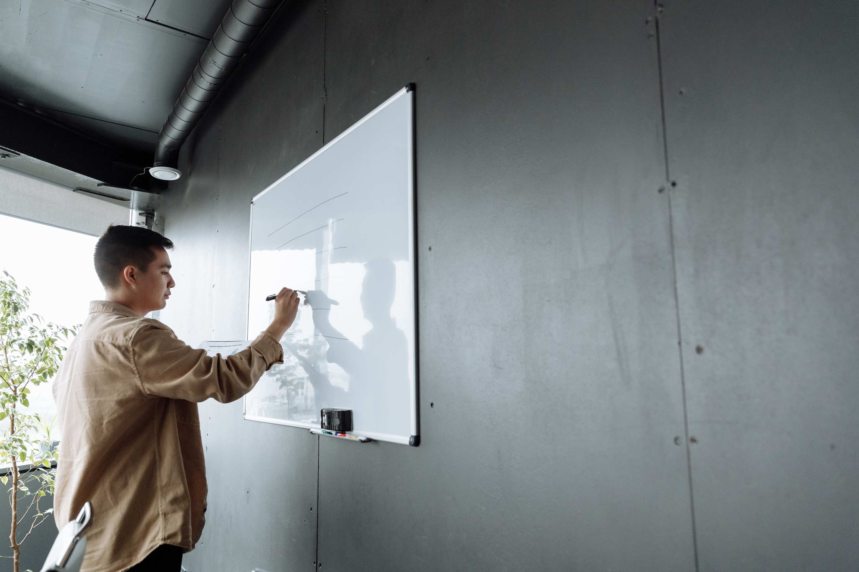Office space with planning boards with an adult writing on a whiteboard in a modern office