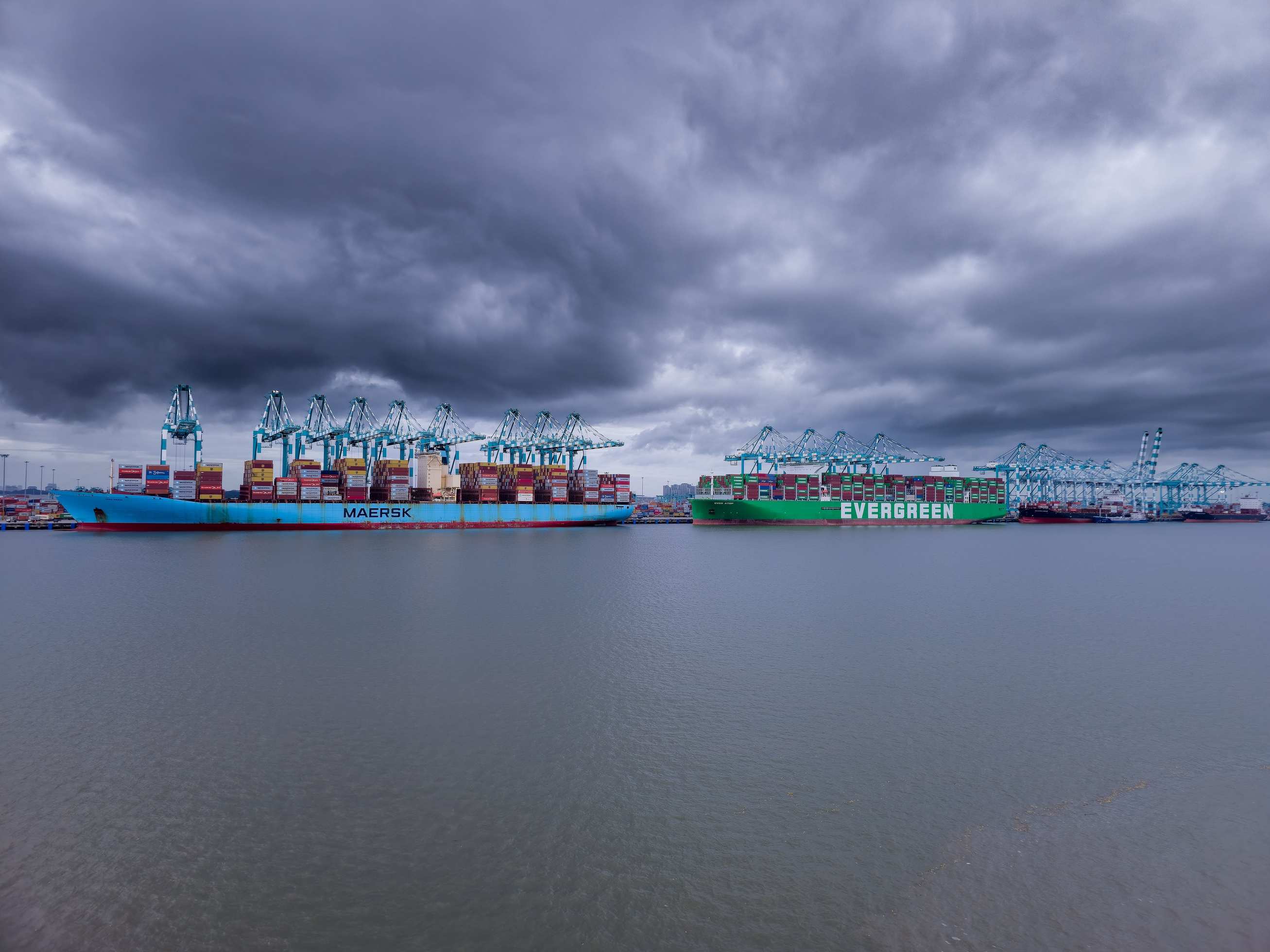 Container ships in a harbor under dramatic storm clouds